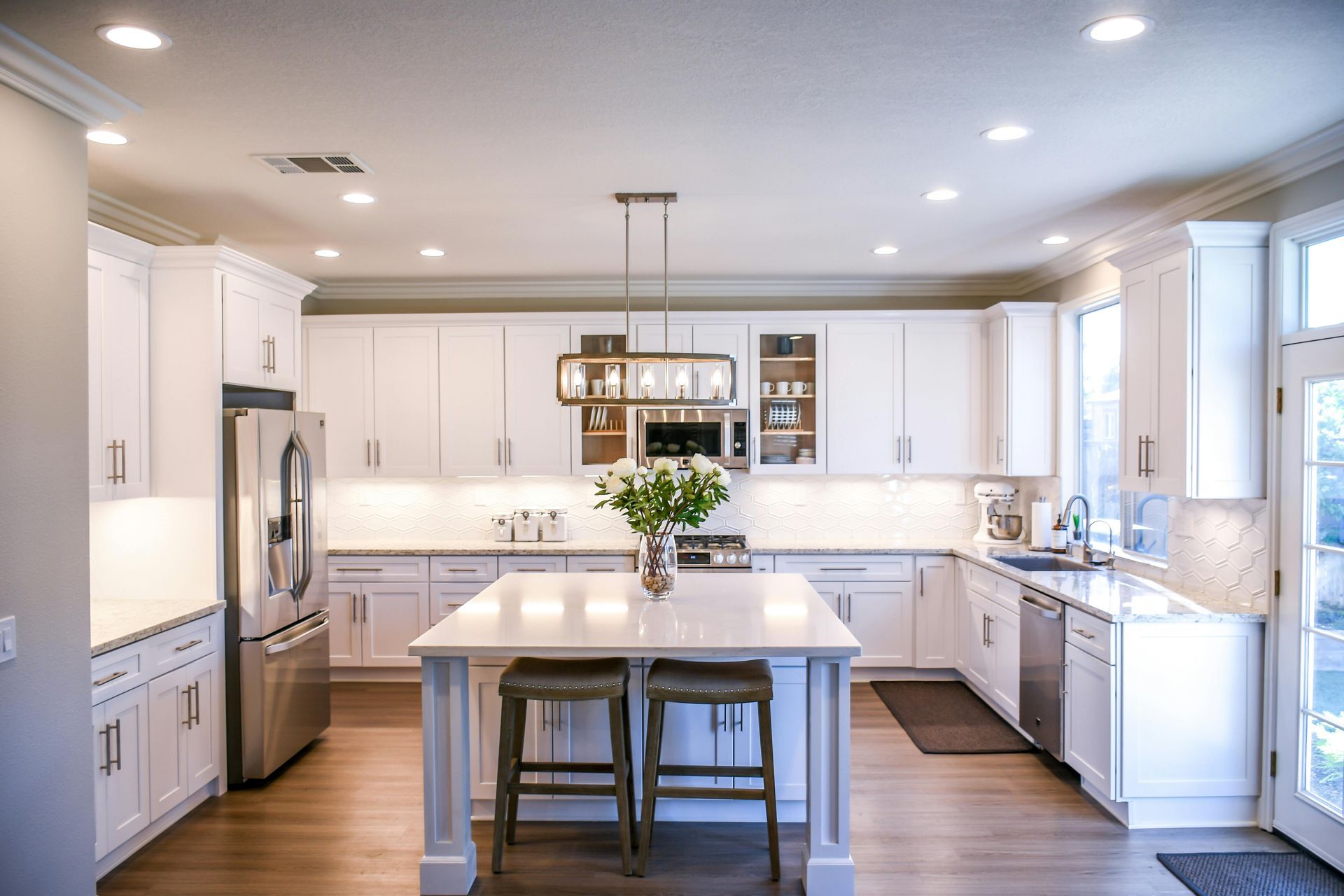 A kitchen with white cabinets, stainless steel appliances, and a large island.