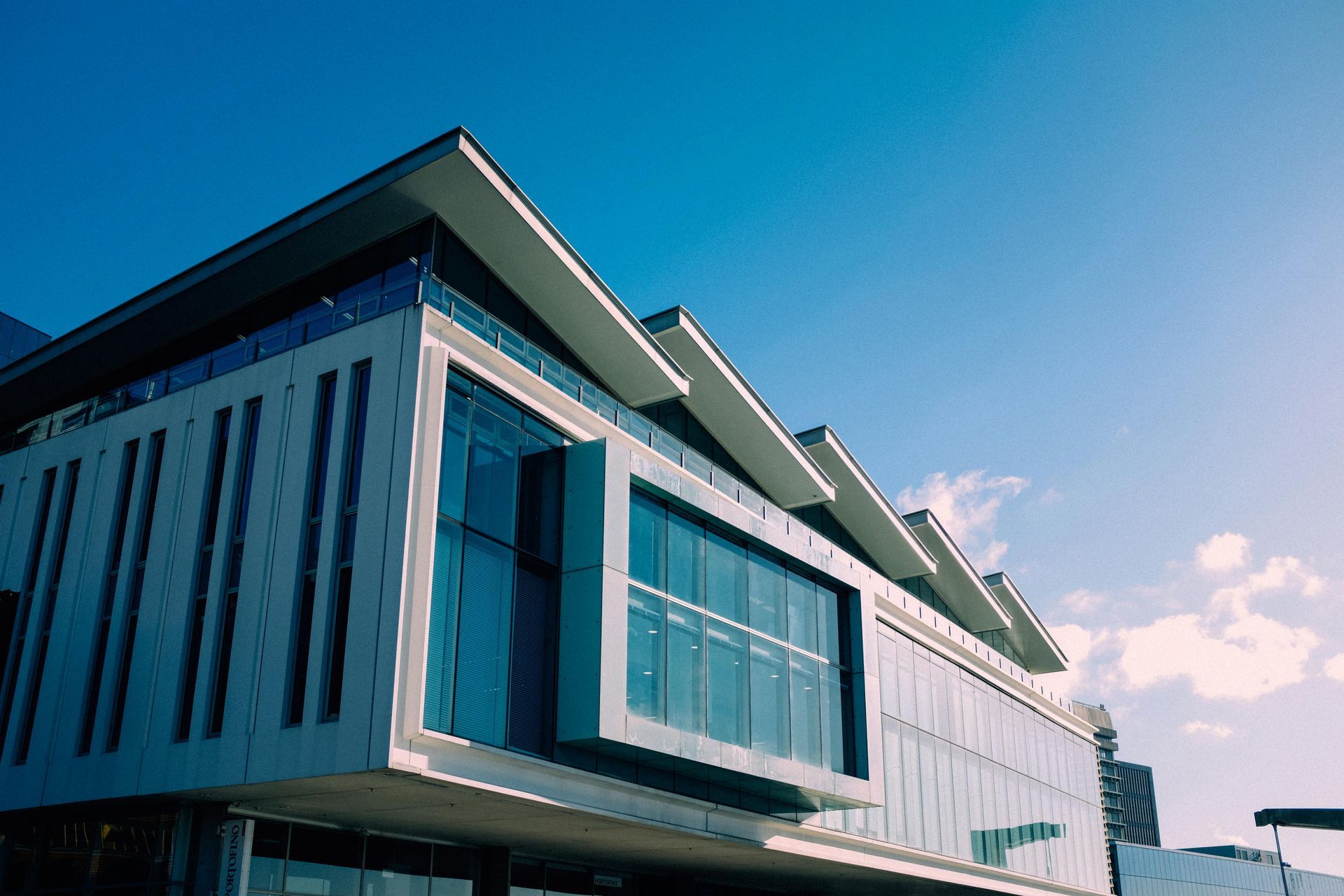 Modern building with a flat roof, glass windows, and a clear blue sky.